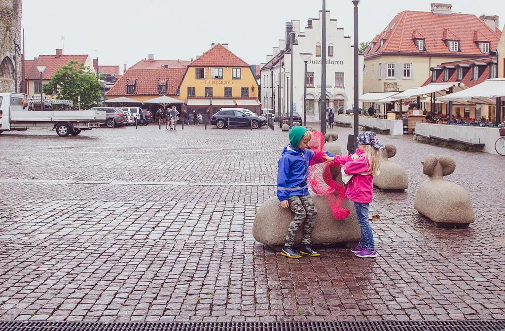 Children handling one of the pink wire figures on a Visby square