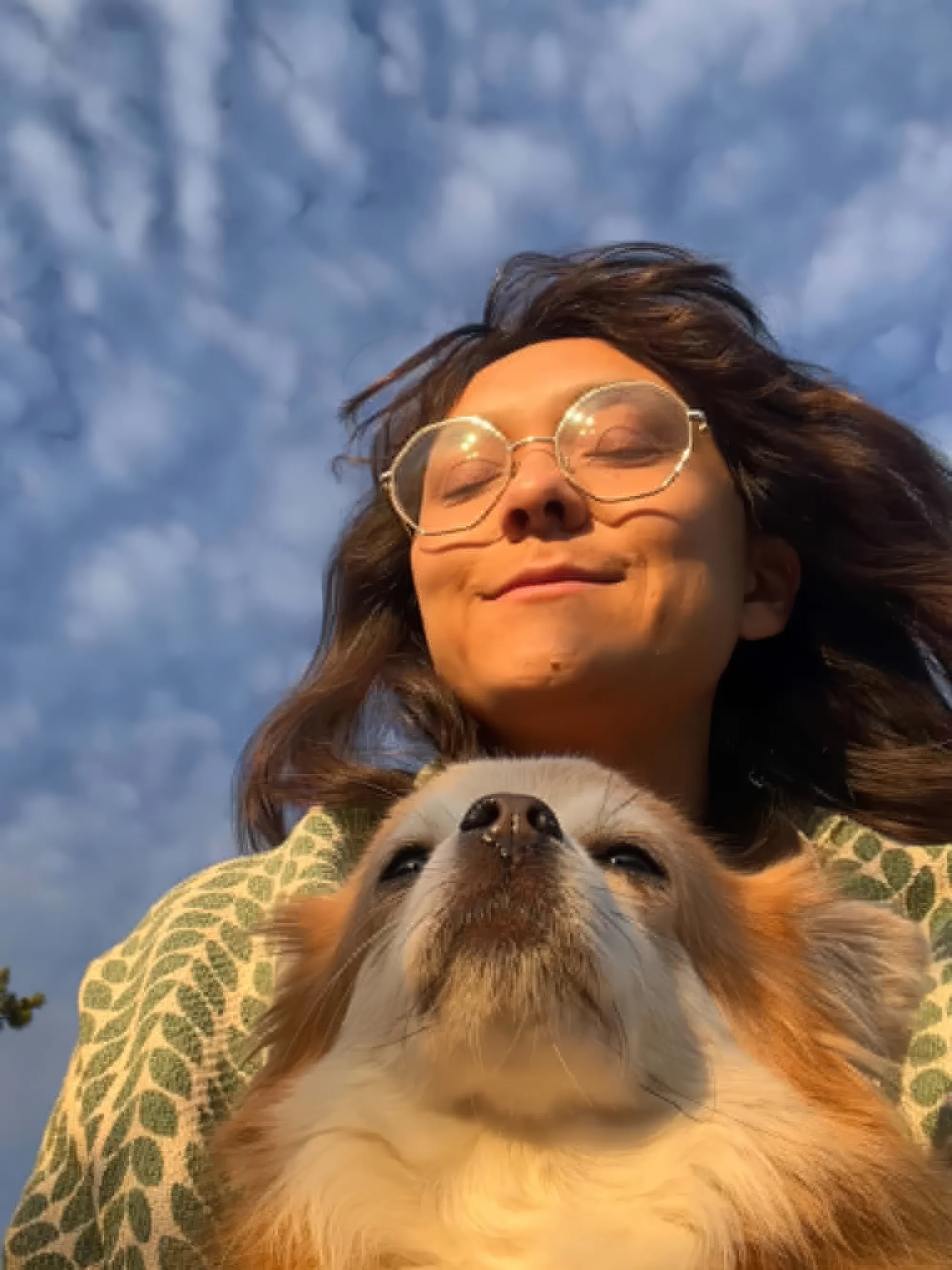 Rose Hallgren outdoors at golden hour, eyes closed, with her dog Sigge against a cloudy sky