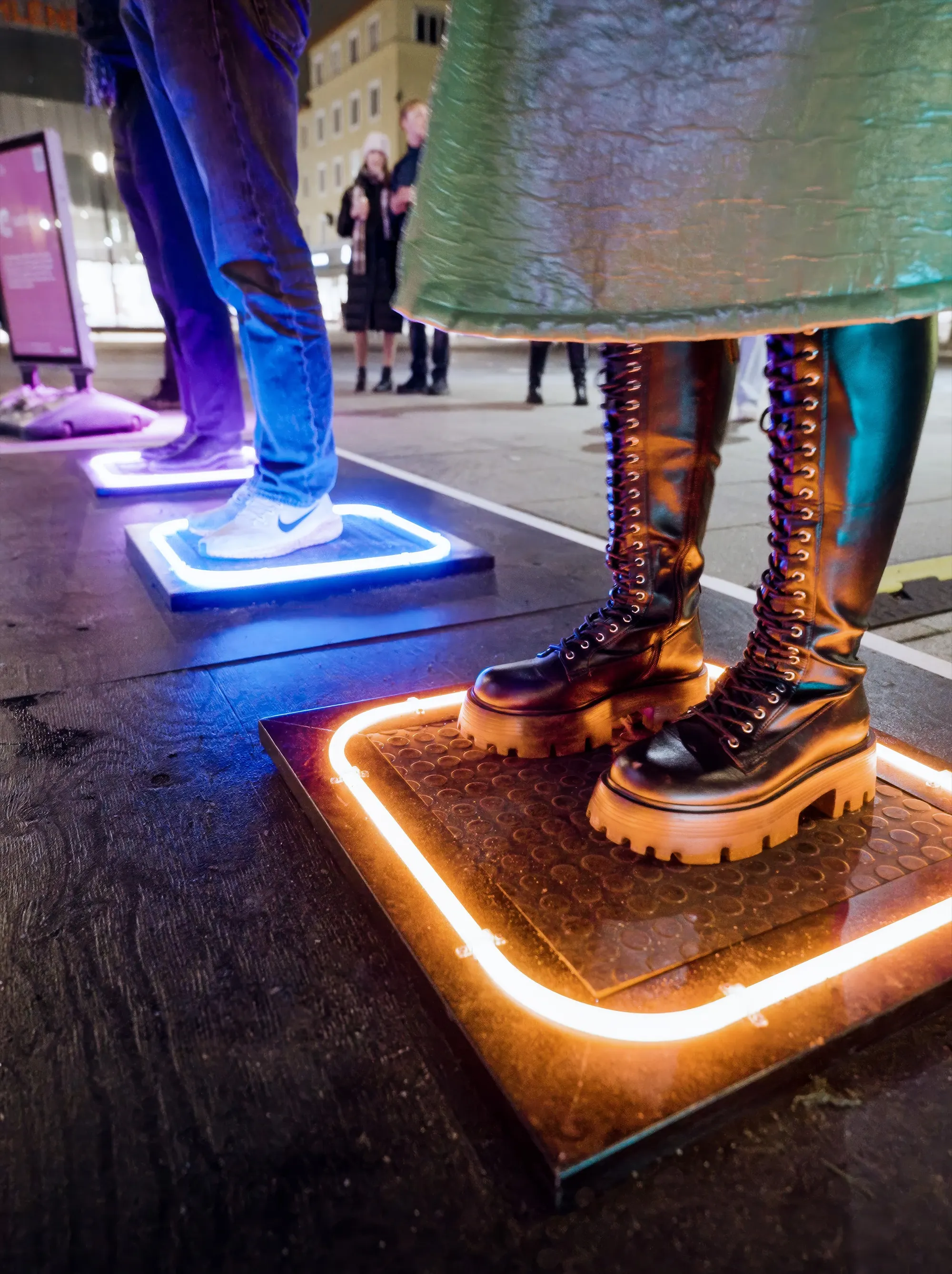 Close-up of a pair of boots standing on one pad, its edge lit white and amber