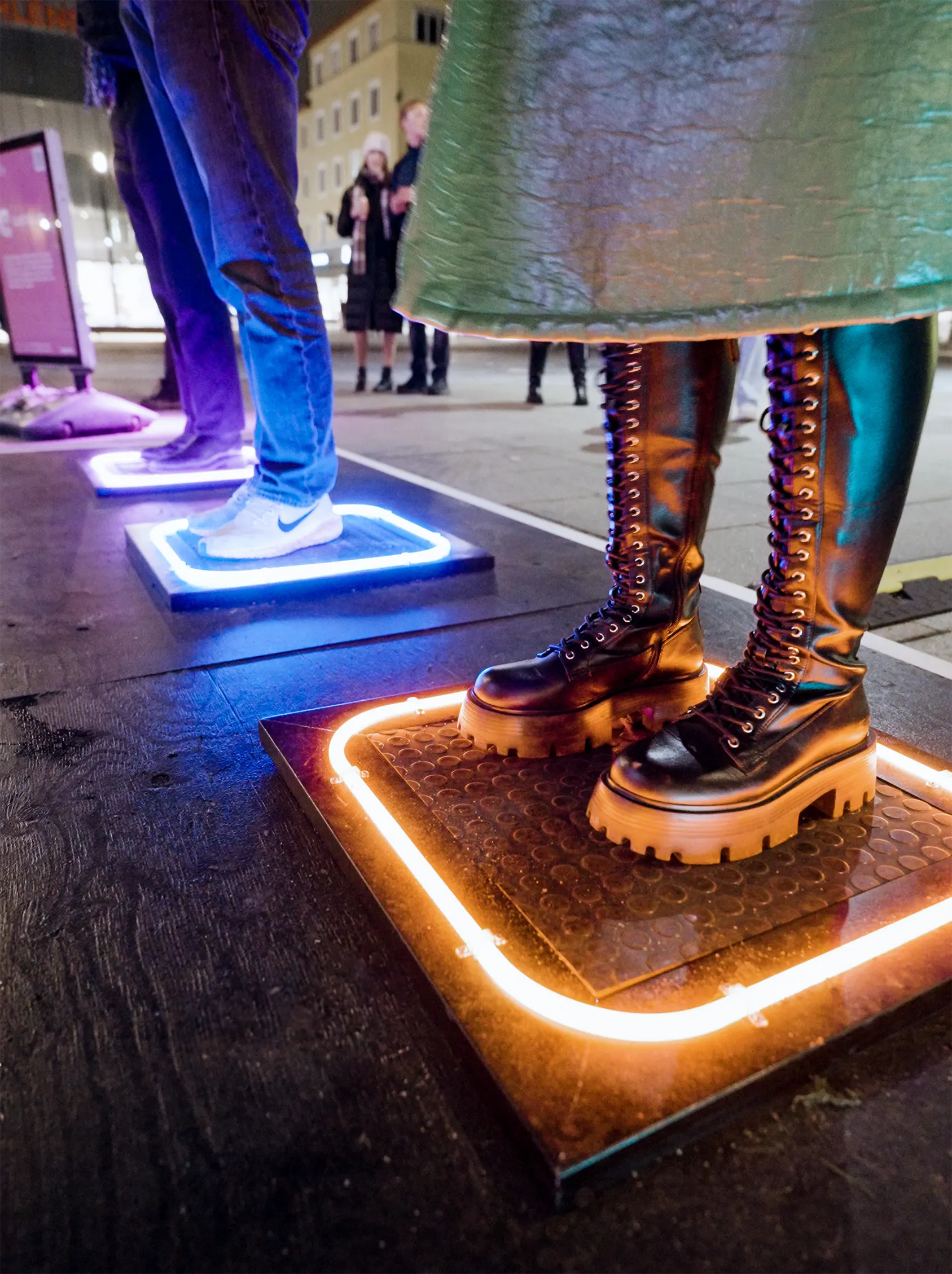 Close-up of a pair of boots standing on one pad, its edge lit white and amber