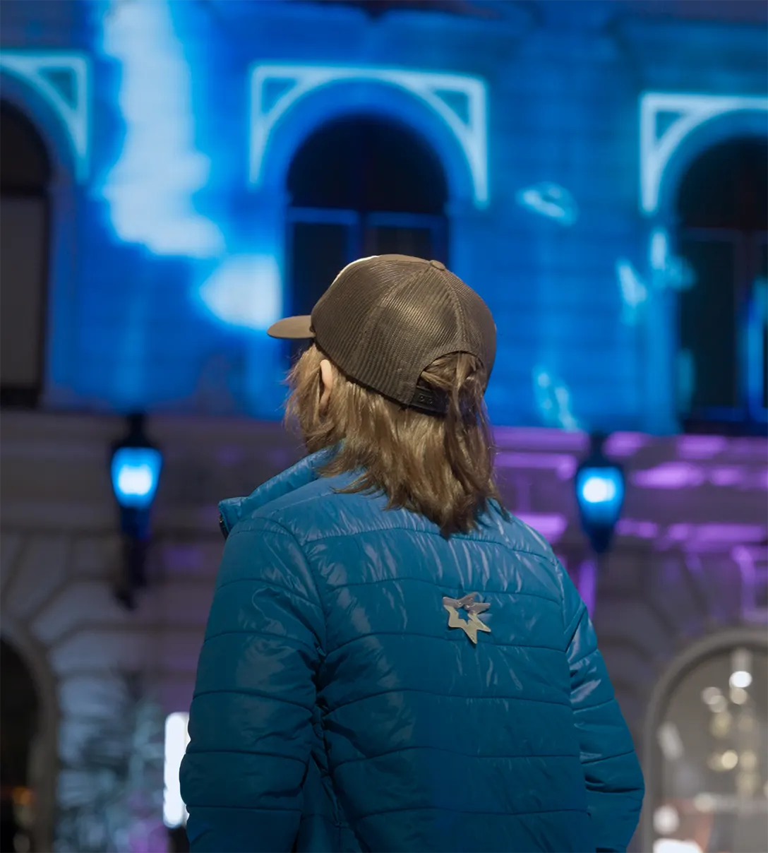 A visitor in a blue jacket watching the projection, two lit pads in front of her