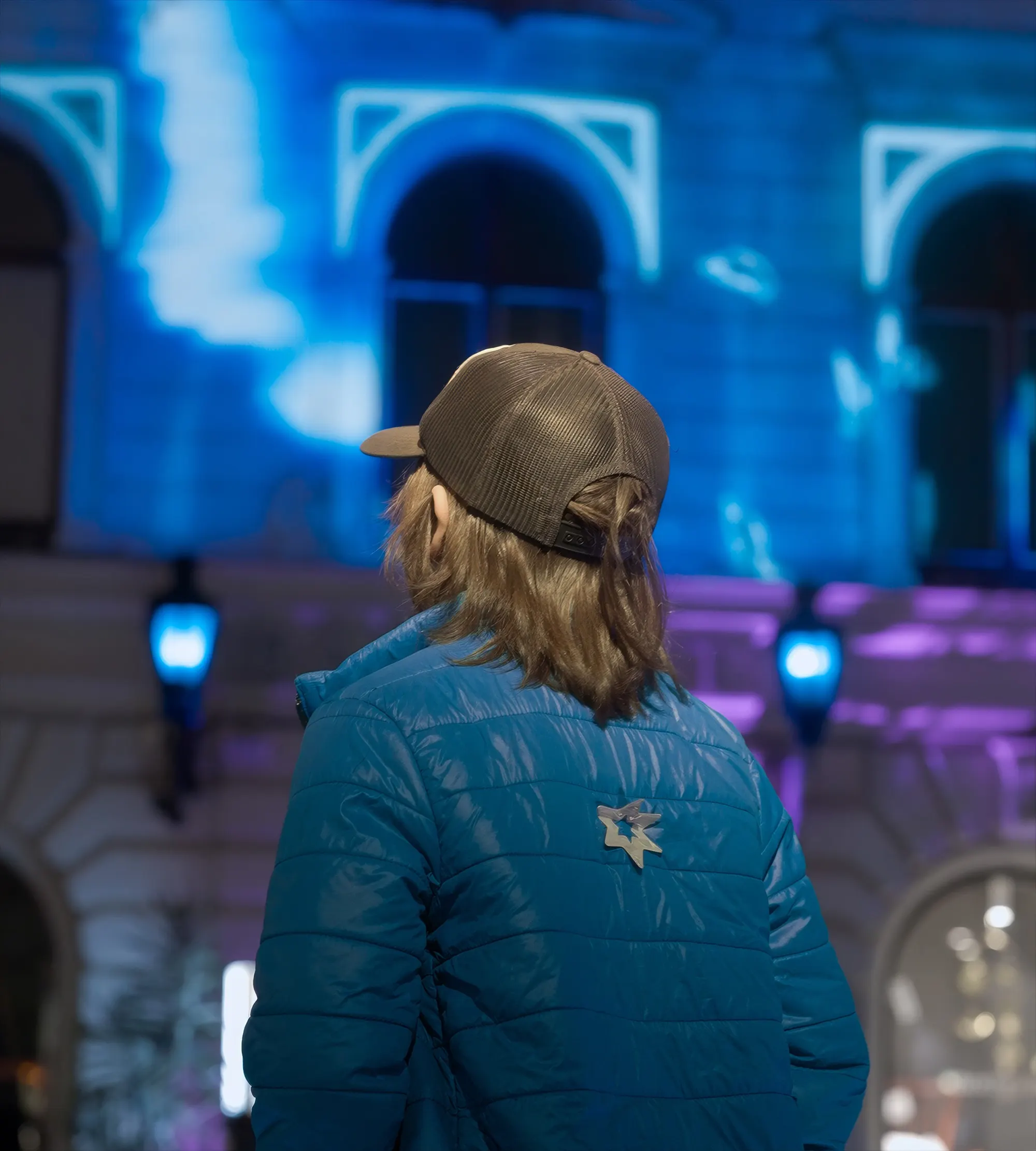 A visitor in a blue jacket watching the projection, two lit pads in front of her